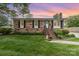 Charming brick home with mature landscaping, black shutters and inviting front porch at 1005 N Main St, Mount Holly, NC 28120