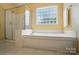 Bright bathroom featuring a large soaking tub, separate glass shower, and a unique frosted block window at 10223 Willingham Rd, Huntersville, NC 28078