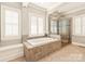 Bathroom with tiled surround tub, stone surround shower, and shuttered windows at 1148 Wessington Manor Ln, Fort Mill, SC 29715