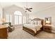 Bright main bedroom features large arched window, shutters, ceiling fan and a wooden bed at 1148 Wessington Manor Ln, Fort Mill, SC 29715