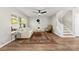 Bright living room with wood flooring, a ceiling fan, and a staircase, creating a cozy atmosphere at 12536 Hennigan Place Ln, Charlotte, NC 28214