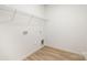 The well-lit laundry room features a clean space with laminate floors and a wall-mounted shelving unit at 1604 Breezewood Dr, Charlotte, NC 28262