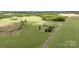 Beautiful aerial view showcases the home and surrounding lush green pastures, complemented by a tree-lined boundary at 1870 Sloan Rd, Mt Ulla, NC 28125