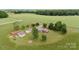 Aerial image of a home with various outbuildings, surrounded by lush greenery and open fields at 1870 Sloan Rd, Mt Ulla, NC 28125