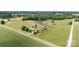 An aerial view of a property with a brick home surrounded by lush greenery, fields, and a quiet country road at 1870 Sloan Rd, Mt Ulla, NC 28125