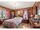 This traditionally styled bedroom boasts wood walls, floral bedding, a display cabinet and matching lamps and curtains at 1870 Sloan Rd, Mt Ulla, NC 28125