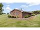This brick home features a metal roof, manicured bushes around the house, and an expanse of land beyond the property at 1870 Sloan Rd, Mt Ulla, NC 28125