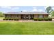 Charming brick ranch home featuring a covered front porch with updated metal roof and manicured landscaping at 1870 Sloan Rd, Mt Ulla, NC 28125