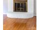 Close-up view of a white brick fireplace with hardwood floors, and a decorative brass screen at 22330 Torrence Chapel Rd, Cornelius, NC 28031