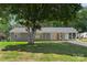 Charming single-story home with a covered carport, gray brick facade, and a large shade tree in the front yard at 2322 Hedgewood Cir, Gastonia, NC 28052