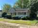 View of the exterior of the house with porch, lawn, and a sidewalk, with overgrown bushes and trees at 2433 Booker Ave, Charlotte, NC 28216