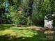 A large yard with lush green grass surrounded by trees and a shed in the back at 2433 Booker Ave, Charlotte, NC 28216