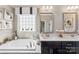 The bathroom features a soaking tub, lots of counter space, decorative mirrors, and excellent natural light at 2511 Carnation Dr, Harrisburg, NC 28075