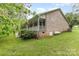 Back exterior view of the brick home featuring a well-kept lawn and propane tank at 302 6Th Sw St, Conover, NC 28613