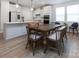 Modern kitchen with white cabinets, stainless steel appliances, a wooden dining table, and beautiful hardwood flooring at 3252 Cheyney Park Dr, Charlotte, NC 28269