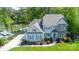 Aerial view of a gray two-story home with stone accents, situated near a lake and featuring lush landscaping at 3992 Blue Dory Ln, Denver, NC 28037