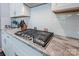 Close-up of a stove top on an island with white cabinets and granite countertops at 3992 Blue Dory Ln, Denver, NC 28037