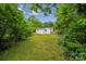 Secluded backyard featuring mature trees, a well-maintained lawn, and the home's exterior, offering privacy and space at 4021 Paisley Pl, Charlotte, NC 28208