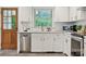 Well-lit kitchen with a stainless steel dishwasher, white cabinetry and gold hardware near a rustic wood door at 4021 Paisley Pl, Charlotte, NC 28208