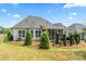 Landscaped backyard featuring manicured shrubs and a stone patio with comfortable seating and a grill at 45523 Misty Bluff Dr, Charlotte, NC 28278