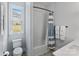 Bright bathroom with a toilet, window, and tiled shower-tub combination with a curtain at 45523 Misty Bluff Dr, Charlotte, NC 28278