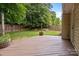 A backyard with green grass and mature trees features a wood deck with string lights at 508 Long Creek Pkwy, Charlotte, NC 28214