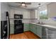 Traditional kitchen with green lower cabinets, a stainless steel sink, and black appliances at 508 Long Creek Pkwy, Charlotte, NC 28214