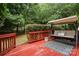 Relaxing outdoor deck with swing seat, red stained wood, and lush greenery at 6729 Garden Hill Dr, Huntersville, NC 28078