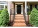Inviting front porch with brick steps, black railings, and lush greenery adding curb appeal at 6729 Garden Hill Dr, Huntersville, NC 28078