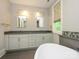 Bright bathroom featuring dual sinks, granite countertops and a luxurious free-standing tub at 7324 Leharne Dr, Charlotte, NC 28270