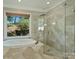 Well-lit bathroom with tub, glass enclosed shower, and view to the outdoors at 9526 Greyson Ridge Dr, Charlotte, NC 28277