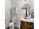 Charming half bathroom featuring a vanity with sink, a round mirror, and a toilet for added convenience at 1004 Craven St, Indian Trail, NC 28079