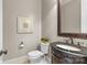 Stylish powder room featuring a dark vanity, framed mirror, and a toilet topped with decorative greenery at 1009 Seminole Dr, Waxhaw, NC 28173