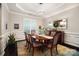 Elegant dining room with wainscoting, tray ceiling, modern chandelier, and hardwood floors at 10115 Paxton Run Rd, Charlotte, NC 28277