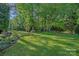 Expansive green backyard with lush landscaping and mature trees offers serene outdoor living at 1400 Coachman Dr, Waxhaw, NC 28173