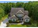 Aerial view of a brick home featuring a lush lawn, landscaped yard, and a long driveway at 1410 Smoketree Ct, Waxhaw, NC 28173