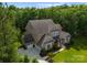 A beautiful aerial view shows the brick home, driveway, manicured lawns, and surrounding trees at 1410 Smoketree Ct, Waxhaw, NC 28173