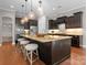 A well-appointed kitchen island with granite counters, dark cabinets, and pendant lights offers seating and ample workspace at 1410 Smoketree Ct, Waxhaw, NC 28173