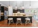 A kitchen features dark cabinets, a granite island with seating, stainless steel appliances, and pendant lighting at 1410 Smoketree Ct, Waxhaw, NC 28173
