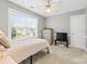 Cozy bedroom with neutral colors, large window, ceiling fan, and television at 14849 Middlesborough Dr, Matthews, NC 28104