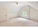 An empty bedroom with an angled ceiling, light carpet, and a window letting in ample natural light at 1504 Alydar Ct, Waxhaw, NC 28173