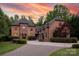 Stunning two-story home with stone accents, lush landscaping, and a paver driveway, set against a vibrant sunset sky at 1504 Alydar Ct, Waxhaw, NC 28173