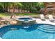 Pool featuring an attached hot tub with a waterfall feature and a nearby tanning ledge at 1504 Alydar Ct, Waxhaw, NC 28173