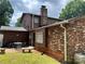 Back exterior of the house with brick and siding, a brick chimney, and an outdoor seating area at 204 Aspen Dr, Gastonia, NC 28052
