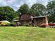 View of a brick home with neatly maintained lawn, mature plants, and a decorative water fountain at 204 Aspen Dr, Gastonia, NC 28052