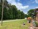 View of grassy road frontage with lush trees; home is slightly visible on the right at 204 Aspen Dr, Gastonia, NC 28052