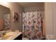 Cozy bathroom with colorful floral shower curtain, vanity, and a well-lit mirror at 217 Hydrangea Dr, Clover, SC 29710
