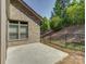 Home showcasing a concrete patio bordered by a metal fence and sloped, wooded backyard at 3002 Portico Pl, Tega Cay, SC 29708