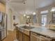 A kitchen island with stainless steel sink and dishwasher complements the stainless steel refrigerator in the open space at 3002 Portico Pl, Tega Cay, SC 29708