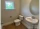 Neutral powder room with a pedestal sink, toilet, and a round mirror at 408 Nathaniel Way # Brx0053, Charlotte, NC 28213